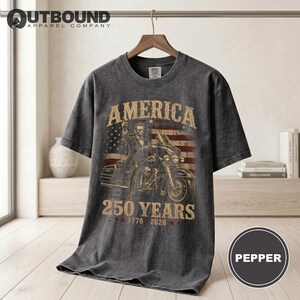 Dark grey t-shirt with "America 250 Years 1776 2026" and a motorcycle rider.