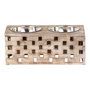 May include: A wooden pet food bowl stand with a woven design and two stainless steel bowls. The stand is light brown with a distressed finish.