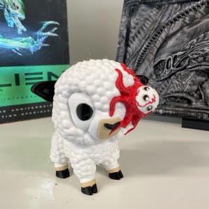 Peut inclure: Figurine de mouton blanc avec des yeux, des oreilles et des sabots noirs. Le mouton a un motif rouge en forme de tentacules sur la tête. Objet de collection unique.