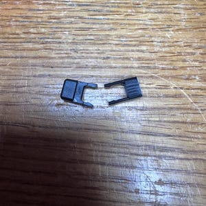 May include: Two black plastic clasps, each with a small hook on one end and a larger hook on the other end.