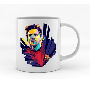 May include: White ceramic mug with a colorful pop art illustration of a soccer player wearing a red and blue jersey with the FC Barcelona logo. The player has a determined expression and is surrounded by geometric shapes.