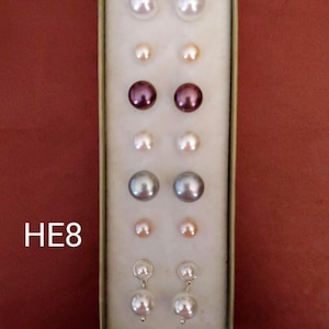 May include: A set of pearl earrings in a box. The earrings are in different colours, including white, pink, grey, and purple. The box is labelled "HE8".