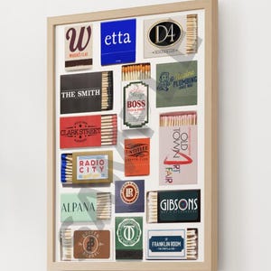 Puede incluir: Un collage enmarcado de etiquetas de cajas de cerillas, con varios nombres de empresas y logotipos, incluyendo "Wetta", "D4", "The Smith", "Clark Street", "Radio City", "Alpana", "Old Town Art Fair", "Gibsons", "Franklin Room" y "Broken Barrel".