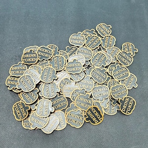 Op de afbeelding: Een verzameling pompoenvormige dranktokens met de tekst "DRINK TOKEN" in een donker lettertype. De tokens hebben een goudkleurige rand en zijn verspreid over een donkergrijze ondergrond.