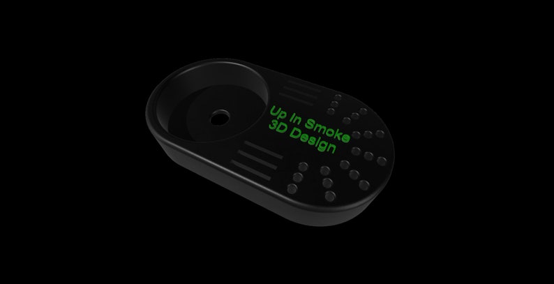 K&ouml;nnte beinhalten: Schwarzes, ovalf&ouml;rmiges 3D-gedrucktes Zubeh&ouml;r mit einer kreisf&ouml;rmigen Schale und einer Reihe kleiner L&ouml;cher und Linien. Der Text "Up In Smoke 3D Design" ist gr&uuml;n aufgedruckt.