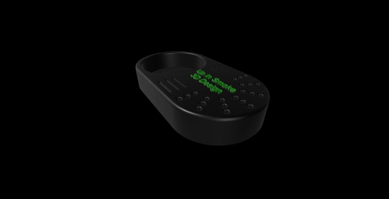 K&ouml;nnte beinhalten: Schwarzer Aschenbecher mit einer kreisf&ouml;rmigen Halterung und einer rechteckigen Basis. Der Aschenbecher hat eine Reihe kleiner L&ouml;cher und den Text "Up In Smoke 3D Design" in Gr&uuml;n. Der Aschenbecher ist f&uuml;r Rauchwaren konzipiert.