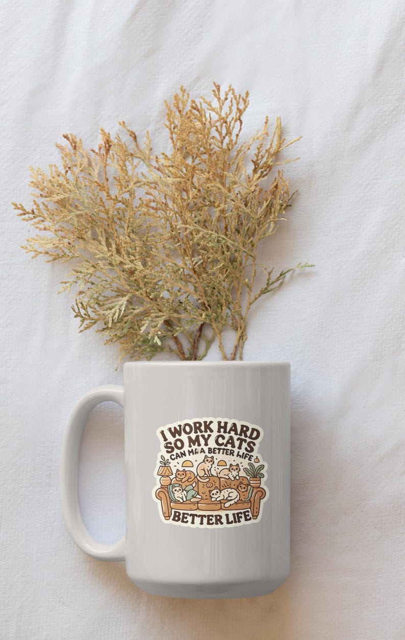 May include: White ceramic mug with a brown and white sticker that says "I work hard so my cats can have a better life" with a cartoon image of cats on a couch.
