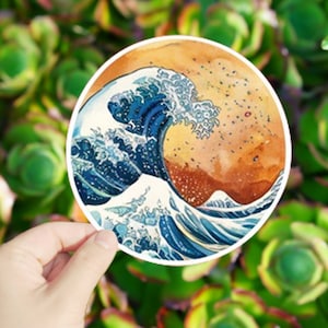 May include: A round sticker featuring a watercolor painting of a large blue wave crashing against a yellow and orange background.