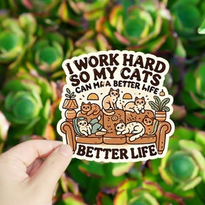 May include: A sticker with a cartoon illustration of cats sitting on a couch. The text reads "I work hard so my cats can have a better life" and "Better Life".