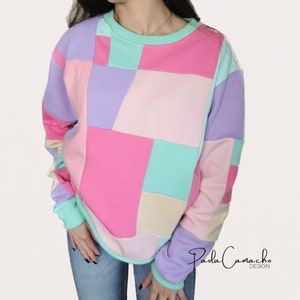 May include: A pastel-colored patchwork sweatshirt with a crew neck and long sleeves. The sweatshirt is made of a soft, comfortable fabric and features a unique design with different colored squares.
