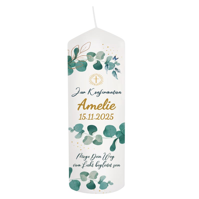 May include: White candle with green eucalyptus leaves and gold accents. The candle has text in German, including the name "Amelie" and the date "15.11.2025". A gold cross is also featured.