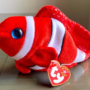 May include: Red and white striped clownfish beanie baby with a blue mouth and a Ty tag that says "Beanie Baby".
