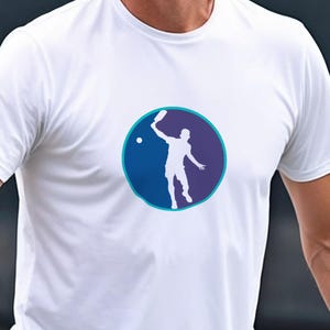 May include: White t-shirt with a blue and purple circle graphic of a silhouette of a person playing tennis.