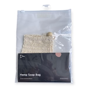 Puede incluir: Una bolsa de plástico transparente que contiene una bolsa de jabón de cáñamo beige y una caja negra. La bolsa de jabón de cáñamo tiene un cierre de cordón con una cuenta de madera. La caja negra tiene las palabras "Hemp Soap Bag" y la marca "Diva".