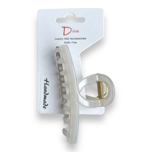 Può includere: Un fermaglio per capelli in plastica bianca con una molla dorata. Il fermaglio è etichettato "Diva Luxury Hair Accessories Static-Free Handmade".