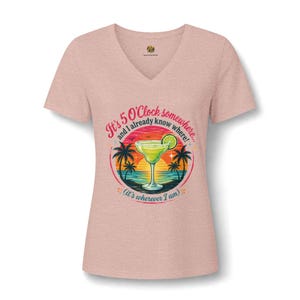 May include: A heathered light pink V-neck t-shirt featuring a graphic of a margarita glass on a beach at sunset. The text reads: It's 5 O'Clock somewhere, and I already know where! (it's wherever I am). The design includes palm trees and a lime slice.