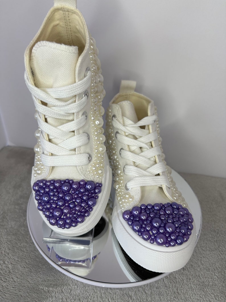 May include: White high-top sneakers with purple and white pearl embellishments.