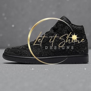 May include: Black high-top sneaker covered in small, sparkling embellishments. The shoe features a black sole, laces, and a logo. The text "Let it Shine DESIGNS" is overlaid on the shoe in a gold color.