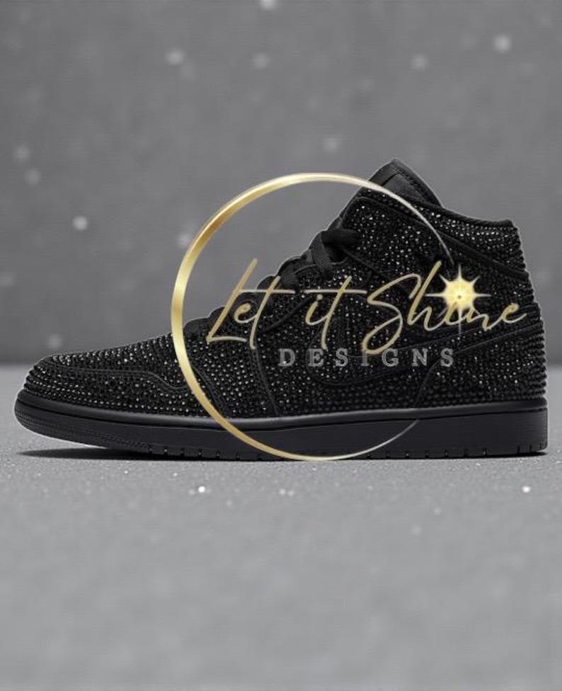May include: Black high-top sneaker covered in small, sparkling embellishments. The shoe features a black sole, laces, and a logo. The text "Let it Shine DESIGNS" is overlaid on the shoe in a gold color.
