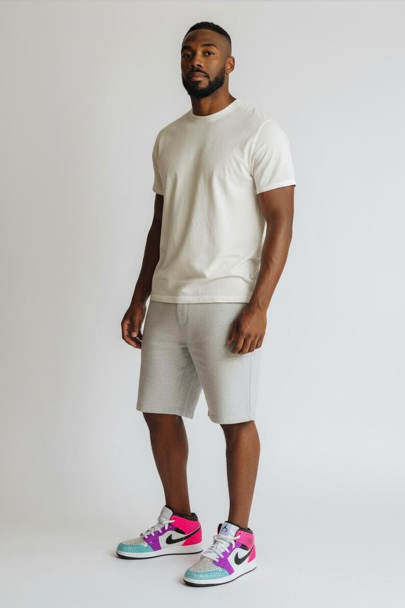 May include: A person wearing a white crew neck t-shirt, gray shorts, and colorful sneakers. The sneakers have pink, purple, and blue accents. The outfit is casual and comfortable, suitable for everyday wear.