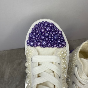 May include: White high-top sneakers with purple and white pearl embellishments.