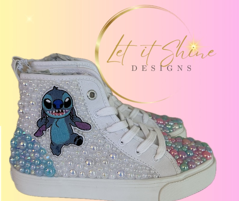 May include: White high-top sneakers with a blue Stitch character appliqu&eacute; and iridescent pearl embellishments. The shoes have a white sole and laces.