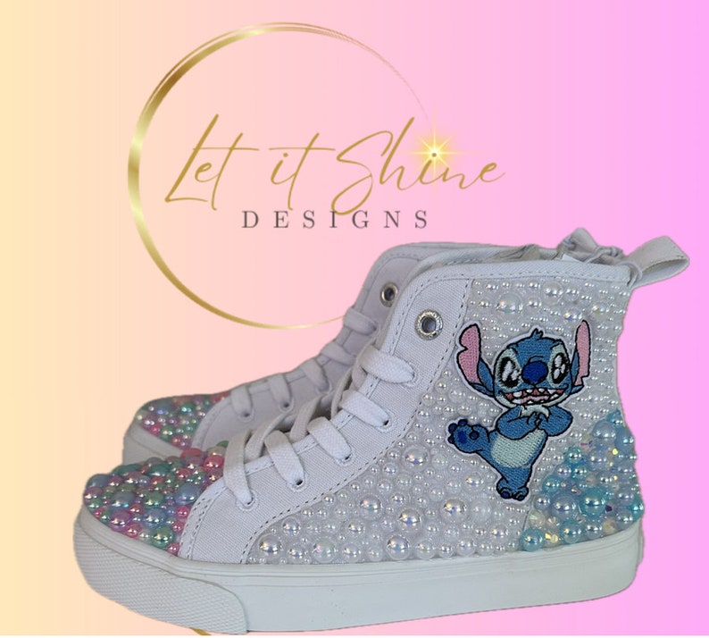 May include: White high-top sneakers with a blue Stitch character embroidered on the side. The shoes are covered in iridescent pearls.