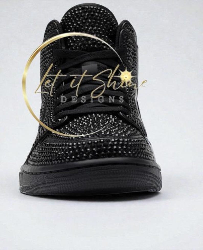 May include: Black high-top sneaker covered in small, sparkling embellishments. The shoe features black laces and a black sole. The text "Let it Shine DESIGNS" is visible in a gold circular design.