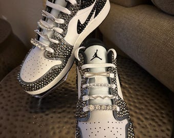 May include: White and black low-top sneakers with a black swoosh logo and rhinestones covering the entire shoe.