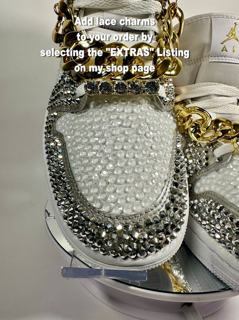 May include: White sneakers with a gold chain and rhinestones. The sneakers have a white leather upper with a gold chain around the ankle. The sneakers are covered in rhinestones. The text "Add lace charms to your order by selecting the "EXTRAS" Listing on my shop page" is written on the image.