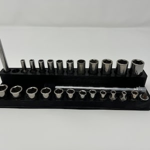 Op de afbeelding: Een zwarte socket organizer met een verscheidenheid aan chromen sockets en een chromen verlengstang. De organizer heeft een gleuf voor een schroevendraaier of ander gereedschap.