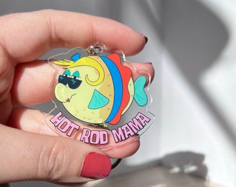 May include: A clear acrylic keychain featuring a cartoon pufferfish with sunglasses and a pink and blue design. The text "Hot Rod Mama" is printed on the keychain.
