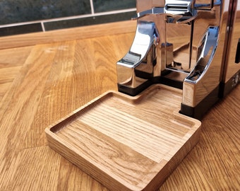 May include: A chrome coffee grinder with a wooden catch tray. The grinder is sitting on a wooden surface.