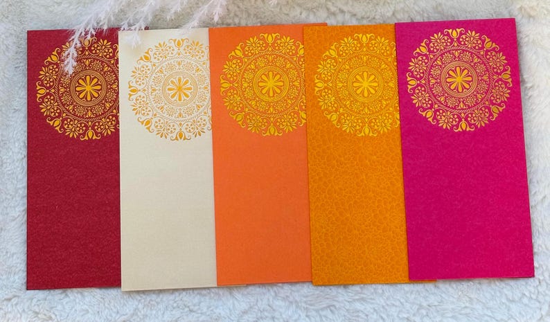 May include: Five blank envelopes with gold mandala designs. The envelopes are red, cream, orange, yellow, and pink.