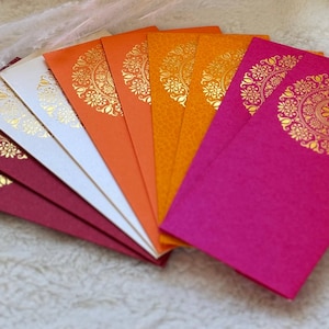 May include: A set of eight decorative envelopes in various colors, including red, orange, yellow, and white. Each envelope features a gold-colored mandala design.