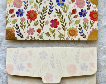 Puede incluir: Un juego de dos sobres con estampado floral y ribete dorado. La parte delantera del sobre tiene un estampado floral colorido con flores rojas, rosas, azules y verdes. La parte posterior del sobre tiene un estampado floral más claro con flores rosas y moradas. El sobre tiene el texto "WM-505" impreso en la esquina inferior derecha.