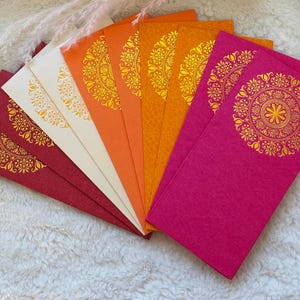 May include: A set of colorful envelopes with gold mandala designs. The envelopes are arranged in a fan shape, with the red envelope at the bottom and the orange envelope at the top.