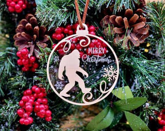 May include: A clear, round Christmas ornament with a silhouette of Bigfoot walking through a snowy forest. The ornament has the text "Merry Christmas" inscribed on it.