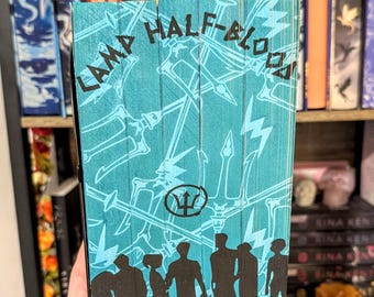 May include: A teal blue book with the title "Camp Half-Blood" in black text. The book cover features a trident symbol, lightning bolts, and silhouettes of people.