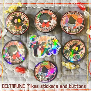 Puede incluir: Una colección de pegatinas y botones Deltarune Mikes coloridos. Los botones presentan varios diseños de personajes con textos como "Mike is a Cat" y "Mike is a Microphone". También se incluye una pegatina holográfica.
