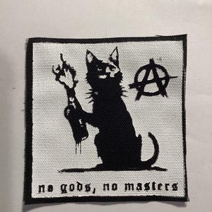 May include: A black and white patch featuring a silhouette of a cat holding a Molotov cocktail, with the anarchy symbol and the text "no gods, no masters". The patch has a white background and a black border.