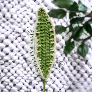 Puede incluir: Una hoja de ganchillo con un centro verde y un borde blanco. La hoja está sobre una superficie blanca y peluda. El texto "PDF PATTERN" está escrito en la imagen.