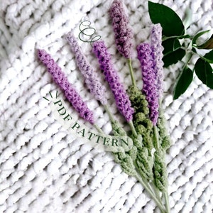 Könnte beinhalten: Ein Strauß gehäkelter Lavendelblüten in Violett- und Grüntönen auf einem weißen Häkelhintergrund. Der Text "PDF PATTERN" ist im Bild sichtbar.