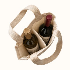 May include: A beige canvas wine tote bag with two internal compartments, each holding a glass bottle. One bottle has a gold-colored cap, and the other has a dark red cap. The bag features two sturdy woven handles and a structured, open-top design.