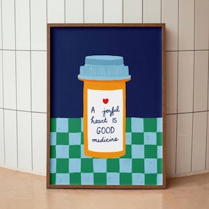 Puede incluir: Una ilustración enmarcada de un frasco de píldoras con tapa azul y cuerpo amarillo. La etiqueta en el frasco dice "Un corazón alegre es buena medicina" con un símbolo de corazón rojo. El fondo es un patrón de cuadros azules.