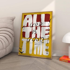 May include: A framed art print with the words "ALL GOD IS GOOD THE TIME" in white and black lettering on a yellow and red background. The artwork is displayed in a room with a neutral color palette.