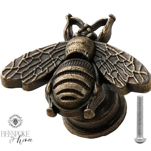 Peut inclure: Un bouton de meuble en forme d'abeille de couleur bronze, avec des ailes et un corps détaillés. Le bouton est livré avec une vis pour l'installation. Le logo "BEE SPOKE home" est en bas à gauche.