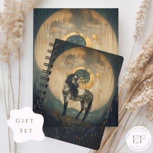 May include: A set of two spiral bound notebooks with a gold and blue design featuring a white horse standing in a field. The cover of the larger notebook has a moon and stars design. The smaller notebook has a horse standing in a field with a moon and stars design. The notebooks are part of a gift set.