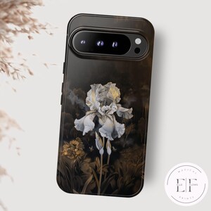 May include: A black phone case with a white iris flower design. The flower is surrounded by gold accents and a dark background.