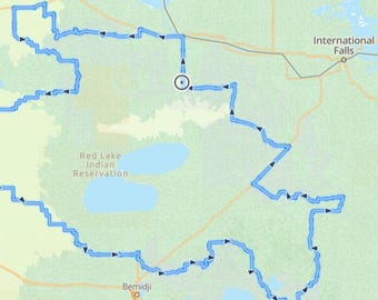 May include: A map showing a blue route around the Red Lake Indian Reservation in Minnesota. The route is marked with black arrows. The map also shows the location of International Falls, Bemidji, and Voyageurs National Park.